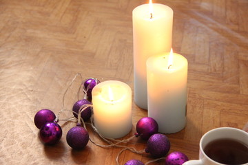 burning candles next to purple garland balls.