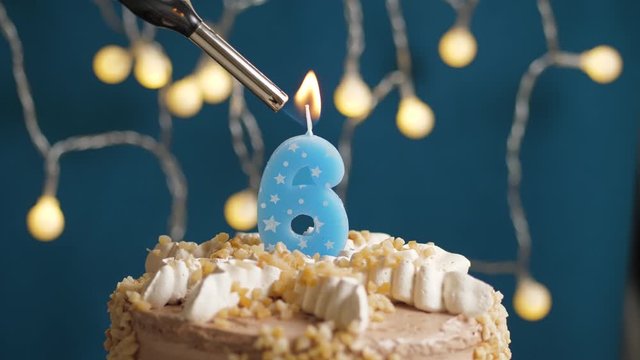 Birthday cake with 6 number candle on blue backgraund. Candles are set on fire. Slow motion and close-up view