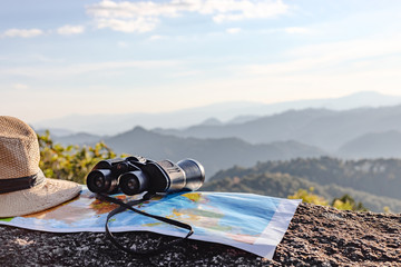 binoculars and map and hat on the rock mountains.