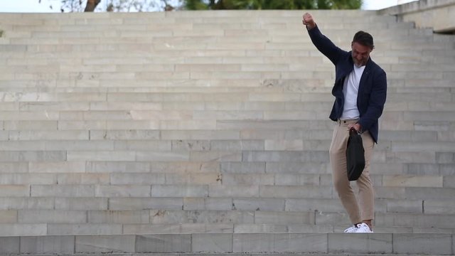 Hombre de mediana edad bailando de alegr&iacute;a con ropa informal con chaqueta y tirantes.