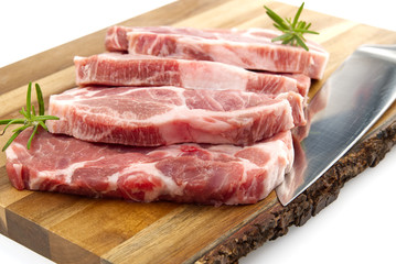 raw pork steak on wood cutting board. Pork with spices: rosemary and pepper. Close-up raw pork steaks.