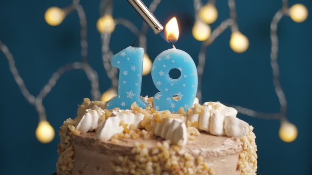 Birthday cake with 19 number candle on blue backgraund. Candles are set on fire. Slow motion and close-up view
