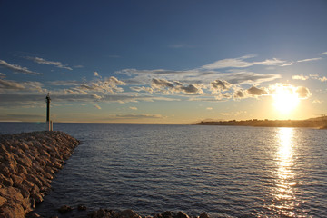 Lighthouse on a stony dike with blue sky