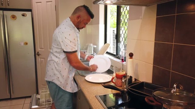 great husband doing housework, cleaning dishes in the sink, washing the dirty dishes, washing plates in the sink, doing house work, keeping tidy