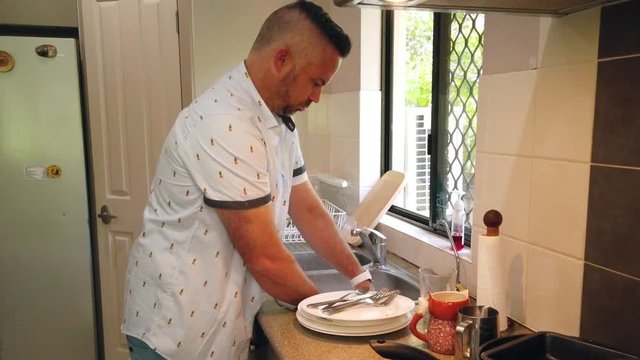 great husband doing the dishes, specifically washing a coffee cup so his wife can have more coffee for breakfast tomorrow
