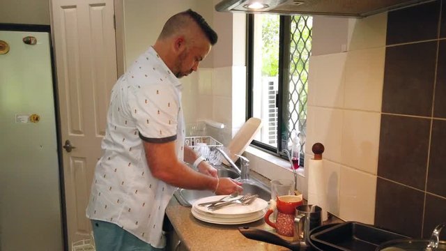 slow motion of great husband washing potato masher in the kitchen sink , doing the dishes , cleaning the plates, dirty dishes, dish washing,