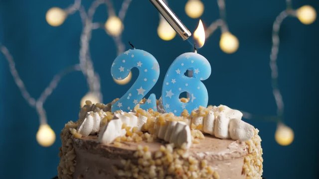 Birthday cake with 26 number candle on blue backgraund. Candles are set on fire. Slow motion and close-up view
