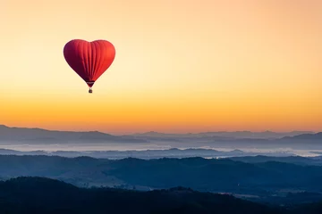 Fototapeten Roter Heißluftballon in Form eines Herzens, das über den Berg fliegt © artpritsadee