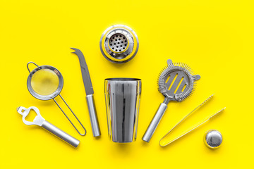 Bartender equipment set with shaker and stainer on yellow background top-down pattern