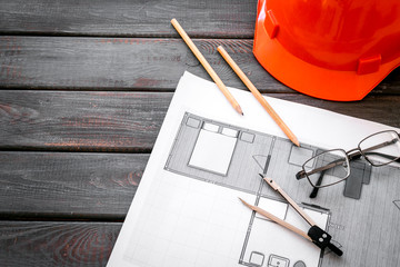 Construction concept. Helmet and blueprints on dark wooden background copy space
