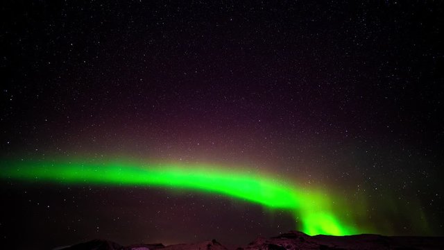 Beautiful green and violet aurora flashing in the night skies with stars in the background - time lapse shot