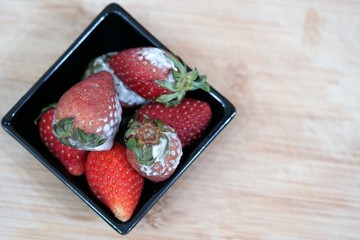 The rotten strawberries with the fungi or mole in the small plate.