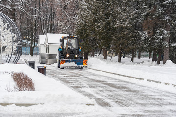 Tractor cleans the snow in the city park