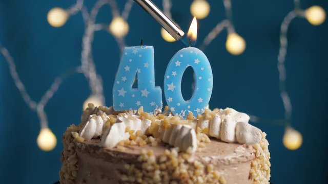 Birthday cake with 40 number candle on blue backgraund. Candles are set on fire. Slow motion and close-up view