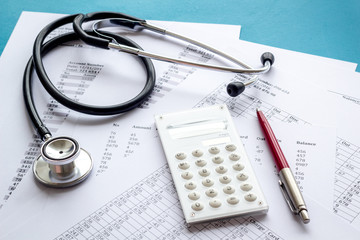 Health insurance concept. Stethoscope near financial documents and calculator on blue background