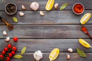 Kitchen frame with spices and food - pepper, garlic, tomatoes - on dark wooden background top-down frame copy space