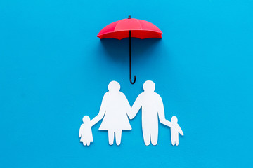 Live insurance concept. Family silhouette protected by umbrella on blue background top-down copy space