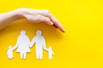 Live insurance concept. Family silhouette under palm on yellow background top-down copy space