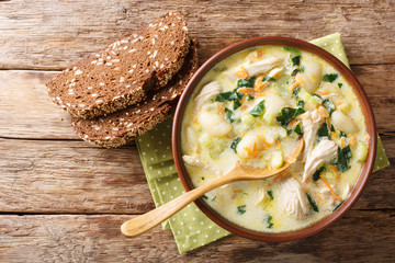 Homemade Italian cream soup with gnocchi, chicken and spinach served with bread close-up in a bowl....