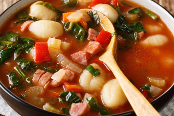 Tuscan tomato soup with gnocchi, Italian sausages and vegetables close-up in a bowl. horizontal