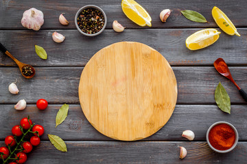 Mockup for menu. Cutting board near spices and vegetables on dark wooden background top-down