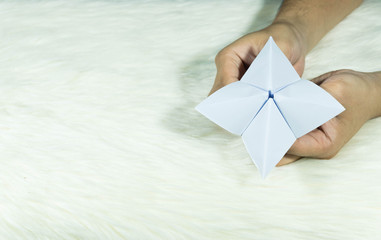 The man's hand is holding a paper that predicts the fate known as Paper Fortune Tellers. To predict the future, work, love, fate, sometimes used as a fun game to play. There is space for copy space.