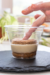 Homemade process of making an Italian tiramisu cake at home. Hand presses cookies on a layer of cream