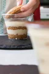 Homemade process of making an Italian tiramisu cake at home. Hand puts cookies on a layer of cream