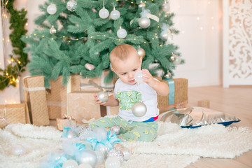 Cute little boy by the Christmas tree and fireplace decorated with garlands and gifts. Christmas...