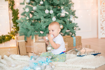 Cute little boy by the Christmas tree and fireplace decorated with garlands and gifts. Christmas...
