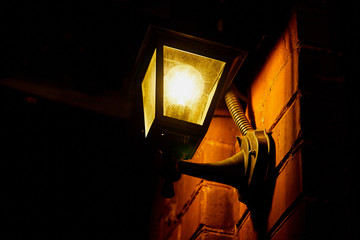Retro lantern on the stone wall and illuminates street on a dark night in the old town