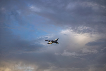Airplane preparing for landing amongst clouds at sunset