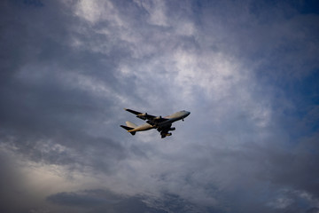 Airplane preparing for landing amongst clouds at sunset