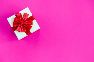 Stylish and beautiful gift box with red bow on pink background