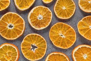 Fototapeta na wymiar Dried oranges sliced in circles on a dark background close-up and top view. Structured orange sliced oranges with a crust in macro.