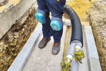 Worker in the knee pads. Black plastic thermally insulated pipe. Long water pipes with thermal...