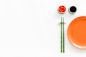 Tableware for sushi and rolls. Plate, chopsticks, bowls with ginger and sause on white background top-down copy space