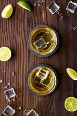 Whiskey near ice cubes on dark wooden background top-down copy space