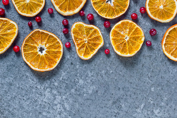 Christmas winter concept frame of chopped dried oranges and red berries with place for text on a dark blue background top view with copy space. Flat lay new year concept greeting card. Xmas mockup.