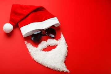 Santa Claus Hat and beard made of snow with black glasses on red background.