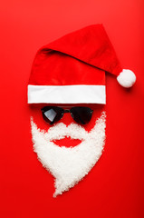 Santa Claus Hat and beard made of snow with black glasses on red background.