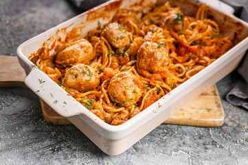 Close-up Spaghetti with meatballs with tomato sauce and herbs in a baking dish. Italian traditional pasta. Mediterranean Kitchen