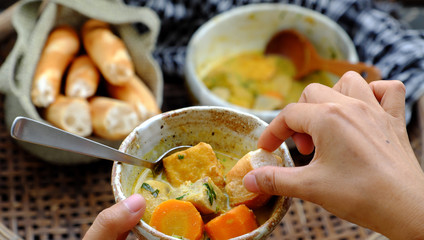People eating delicious yellow vegan curry dish bowl with bread for breakfast