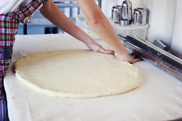  Hands working with bread dough recipe preparation. Female hands making dough. Women's hands roll out the dough. Mom rolls dough on a kitchen board with a rolling pin