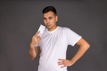 A young man in a white t-shirt holds a business card