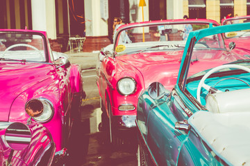 Vintage colored classic american cars front of the Galician Palace on Prado Street in Havana, Cuba.