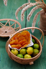 Vietnamese traditional food for tet, homemade kumquat jam and raw material in basket on green wooden background