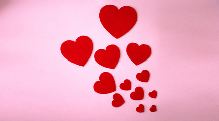 Paper hearts on a pink background. Twelve paper hearts of different sizes.