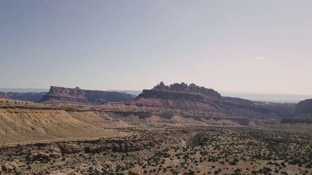 Incredible beautiful drone footage flying down from mesa rock over desert valley, bushes and landscape in Black Dragon Canyon in Green River, Utah, United States