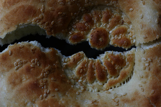 roken bread cake with sesame seeds on a dark background